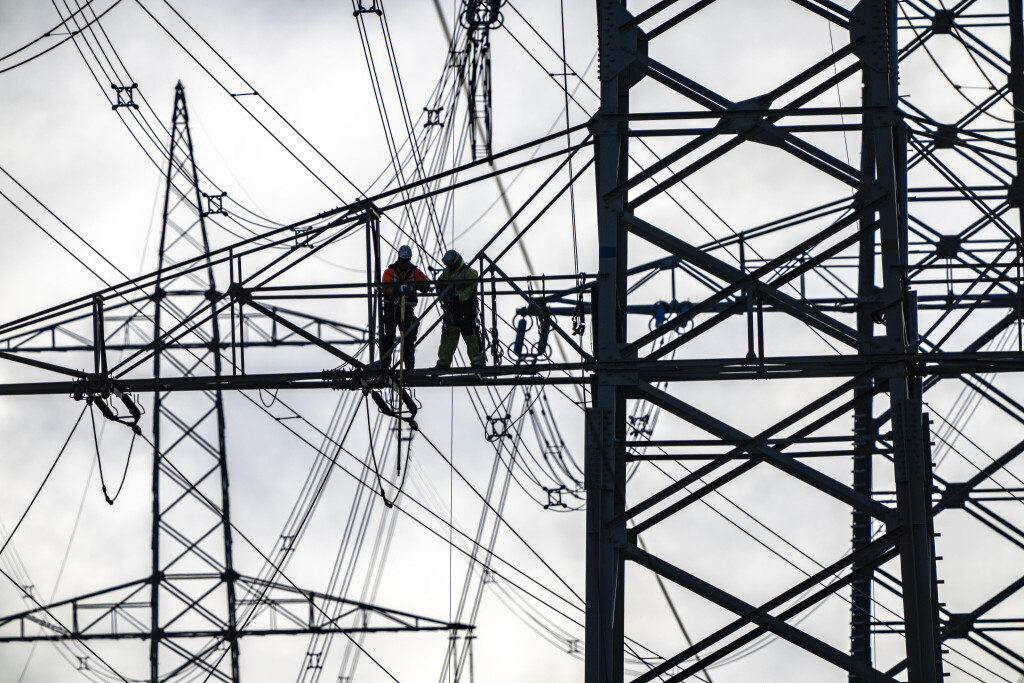 Arbeiten an einer 380-kV Höchstspannungsfreileitung, Neubau, entlang der Autobahn A57, bei Meerbusch, Arbeiter auf den Auslegern des Hochspannungsmasts, NRW, Deutschland,